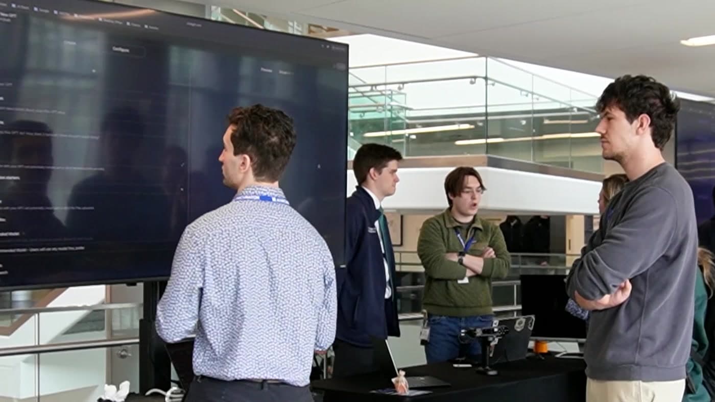 AI Incubator members reviewing work together beside a large display